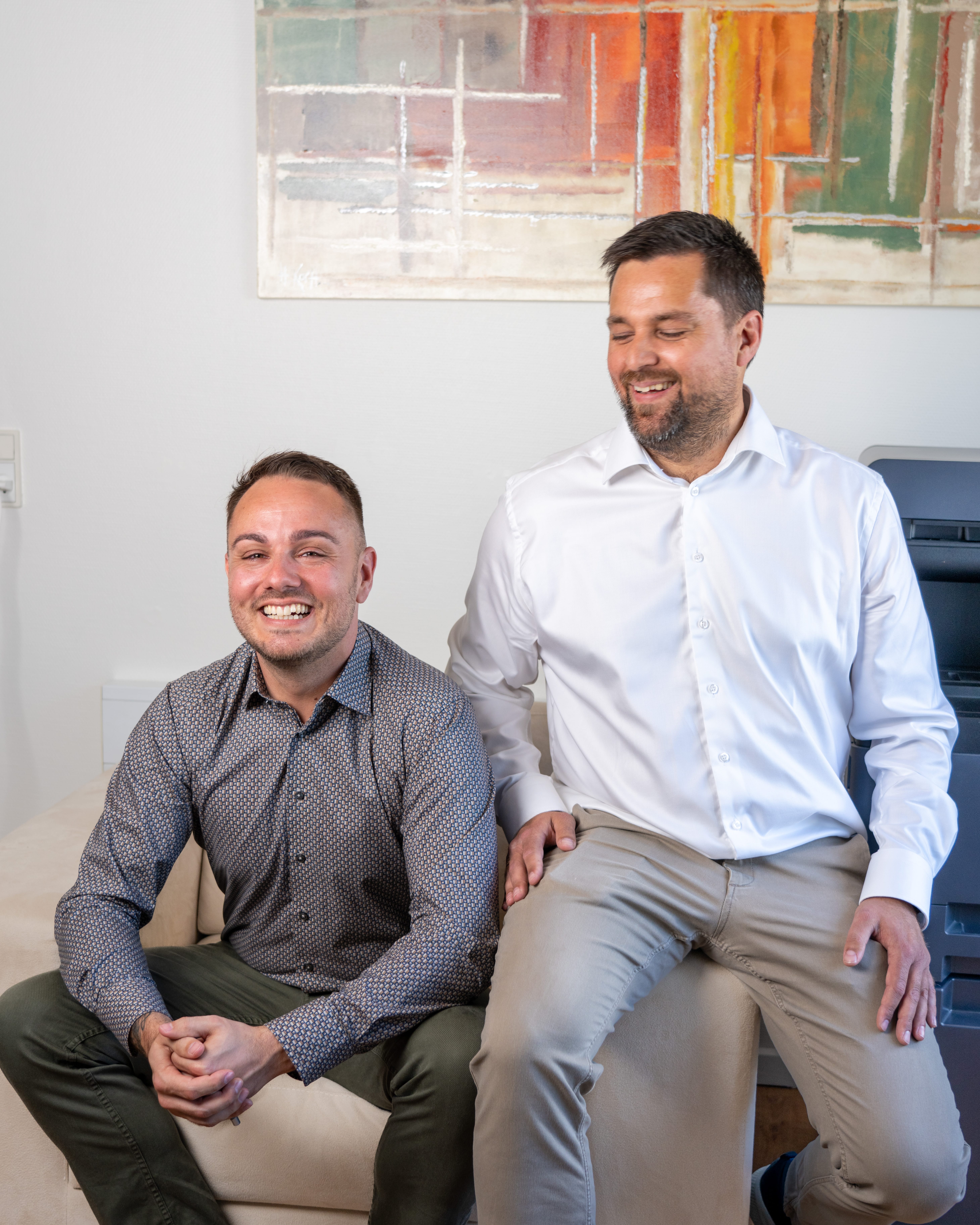 To mænd smiler i moderne kontormiljø